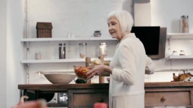 Gülümseyen kadın salata ve mısır koyuyor. 