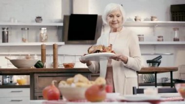 Gülümseyen kadın masaya lezzetli bir hindi koyuyor. 