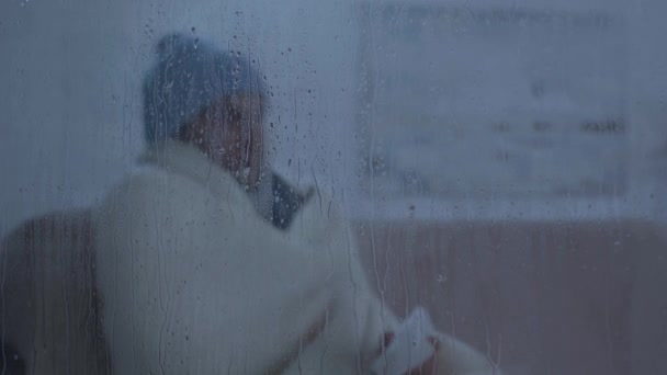 病人坐在靠窗的玻璃杯边 身上滴着雨点 打喷嚏到餐巾纸上 — 图库视频影像