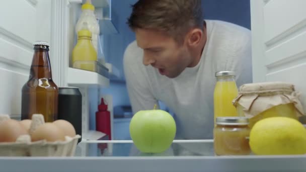 Hungrig Man Tittar Kylskåp Äpple Och Stänga Dörren — Stockvideo