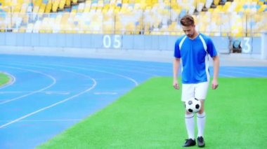 Futbolcu oturuyor ve top zıplıyor 