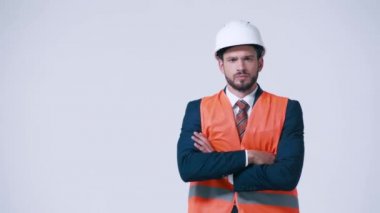 Çapraz kollu, çelik yelekli ve kasklı ciddi bir mimar.