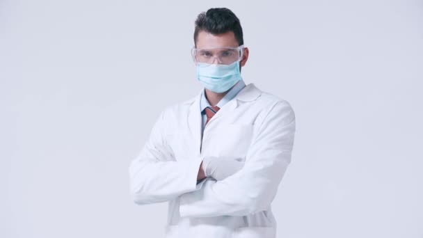 ホワイトで隔絶された腕を持つゴーグルや医療用マスクの深刻な医師 — ストック動画