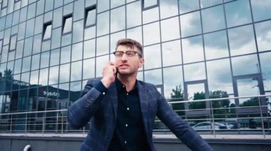 Gözlüklü yakışıklı dışarıda akıllı telefondan konuşuyor.