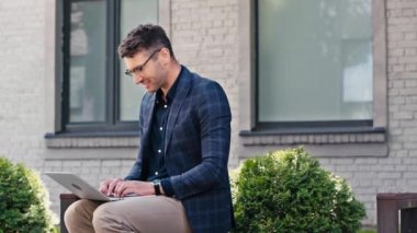 Dışarıda dizüstü bilgisayarda klavyede yazan mutlu serbest yazar.