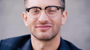 Yakından bakınca yakışıklı bir adam gülümsüyor ve kameraya bakıyor.