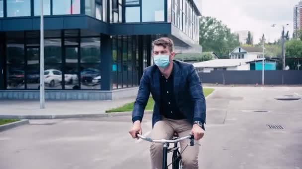 Άνθρωπος Ιατρική Μάσκα Ιππασία Ποδήλατο Στην Άσφαλτο Κοντά Στο Κτίριο — Αρχείο Βίντεο