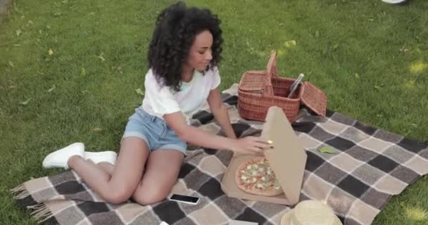 Uśmiechnięta Afroamerykanka Otwierająca Pudełko Pizzy Podczas Pikniku Parku — Wideo stockowe