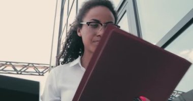 Afro-Amerikalı iş kadını şehir sokaklarında gazetelere bakıyor.