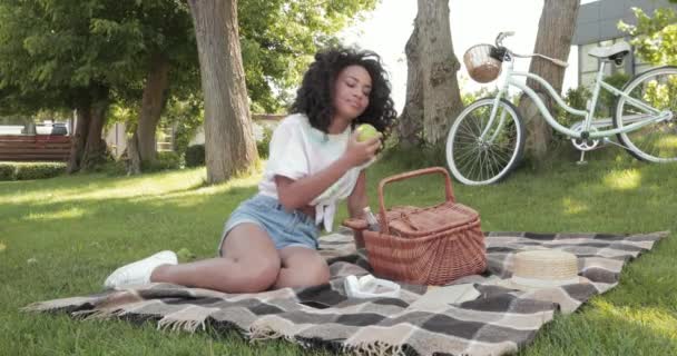 Αφροαμερικανή Γυναίκα Τρώει Μήλο Κατά Διάρκεια Πικνίκ Στο Γρασίδι Στο — Αρχείο Βίντεο