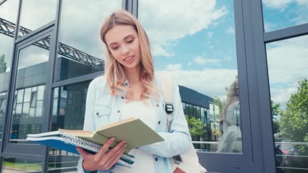 Uśmiechnięty Student Czyta Książkę Pobliżu Budynku Ulicy Miejskiej — Wideo stockowe