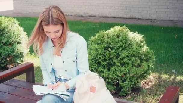 Student Pisanie Notebooku Siedząc Ławce Ulicy Miejskiej — Wideo stockowe