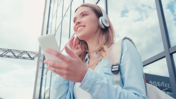 Vrolijke Student Koptelefoon Met Smartphone Buurt Van Gebouw Stedelijke Straat — Stockvideo