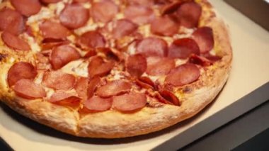 Gri arka planda karton kutularda salamlı pizza çeviriyorum.