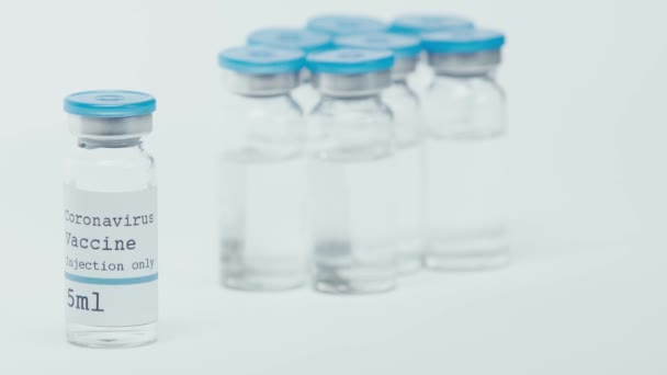 白色のコロナワクチンの入った瓶の近くに注射器を持った人の — ストック動画