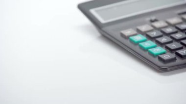 Beyaz arkaplanda hesap makinesinin yanına düşen dolarların seçici odağı