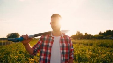 Sakallı çiftçi ayakta ve tarlada kürek tutuyor. 