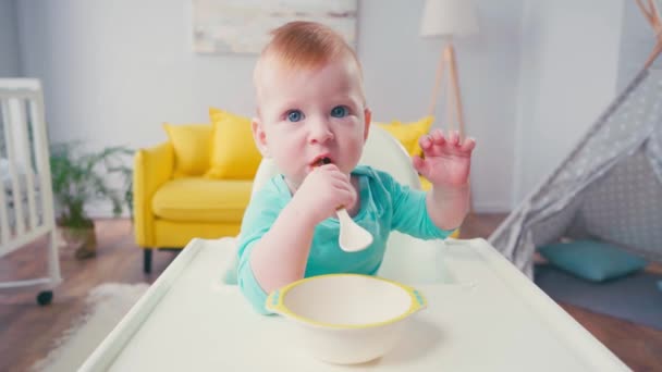 Menino Sentado Cadeira Bebê Chupando Colher Perto Tigela — Vídeo de Stock