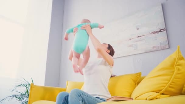 Mother Holding Arms Barefoot Infant Son While Sitting Sofa — Stock Video