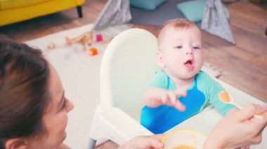 Esmer anne bebeğe mama veriyor. 