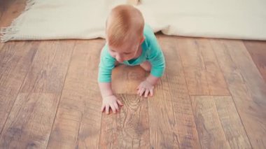 Küçük çocuk sürünüyor ve kameraya bakıyor.