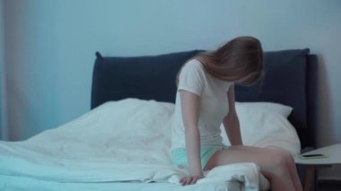 Uykulu kadın gece yatağında oturuyor.