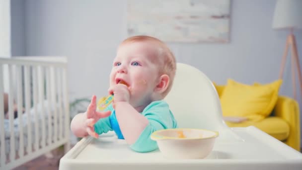 Menino Bebê Chupando Colher Com Comida Bebê Perto Tigela Mesa — Vídeo de Stock