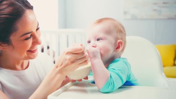 黑发女人用婴儿食品喂兴奋的婴儿 — 图库视频影像
