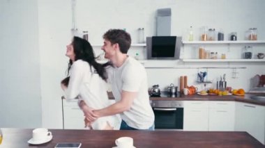 Erkek, mutfakta seksi kız arkadaşıyla sarılıp dans ediyor. 