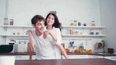 İç çamaşırlı ve gömlekli bir kadın masadaki kahvenin yanındaki erkek arkadaşa sırnaşıyor. 