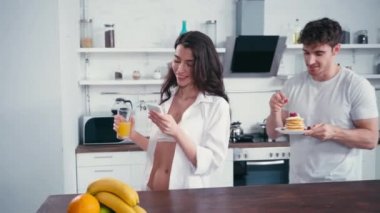 Krepli adam mutfakta akıllı telefonla seksi kız arkadaşını besliyor. 