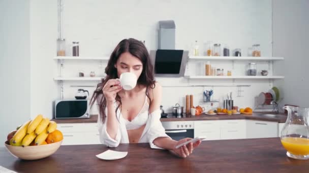 Kobieta Biustonoszu Koszuli Pije Kawę Używa Smartfona Kuchni — Wideo stockowe
