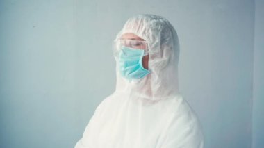 Tehlikeli madde giysisi ve tıbbi maske takan bilim adamı gri eldivenler giyiyor.