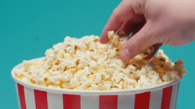 İnsanların patlamış mısırı büyük kovadan alıp mavi renkte izole edişinin yakın görüntüsü.