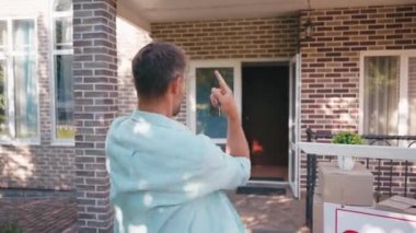 Heyecanlı adam yeni evi işaret ediyor, bağırıyor ve dışarı zıplıyor.