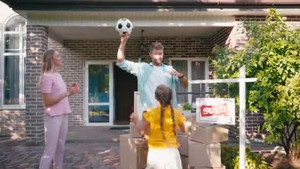 Kids throwing football to parents near carton boxes and new house — Stock Footage Kids Throwing Football Parents Carton Boxes New House Stock Video
