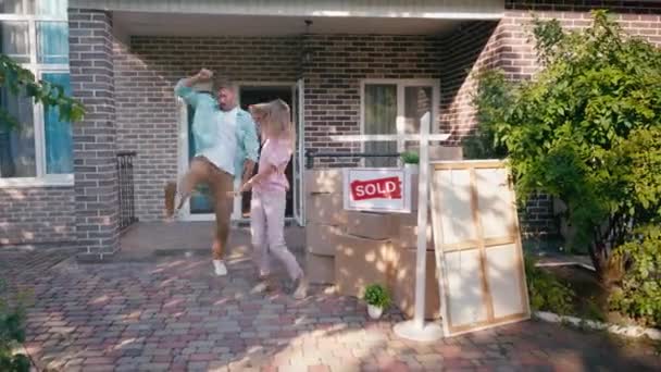 Joyful couple jumping and dancing near boxes and new house — Stock Footage Joyful Couple Jumping Dancing Boxes New House Royalty Free Stock Footage