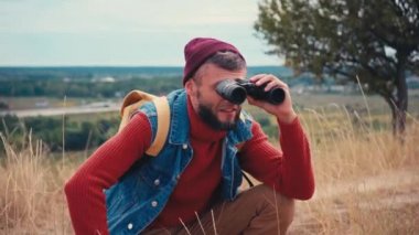 Gezgin oturuyor ve dürbünle dışarı bakıyor.