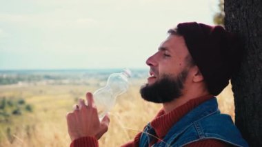 Ağacın yanında su içen adamın yan görüntüsü