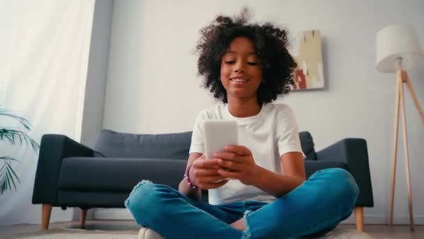 Chica Afroamericana Con Las Piernas Cruzadas Usando Teléfono Celular Mientras — Vídeos de Stock