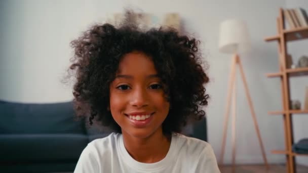 有选择地聚焦于微笑的非洲裔美国女孩在家里看着相机 — 图库视频影像