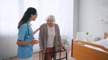 Doktor eliyle işaret ediyor ve aylaklarla yürüyen kadınla konuşuyor.