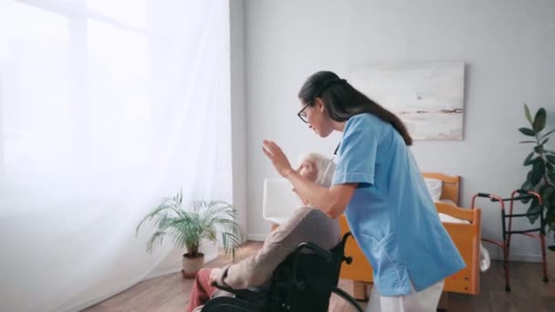 Hermana Geriátrica Señalando Con Mano Mientras Mueve Paciente Silla Ruedas — Vídeo de stock