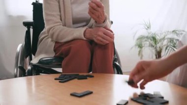 Yaşlı kadın ve hemşire hastanede domino oynuyorlar.