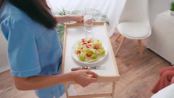 Geriatrische Verpleegkundige Dragen Lade Met Ontbijt Naar Oudere Patiënt — Stockvideo