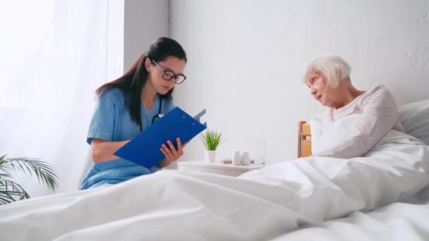 Elderly Woman Bed Talking Geriatrician Writing Clipboard — Stock Video