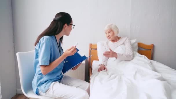 Jovem Geriatra Conversando Com Paciente Idoso Escrevendo Área Transferência — Vídeo de Stock