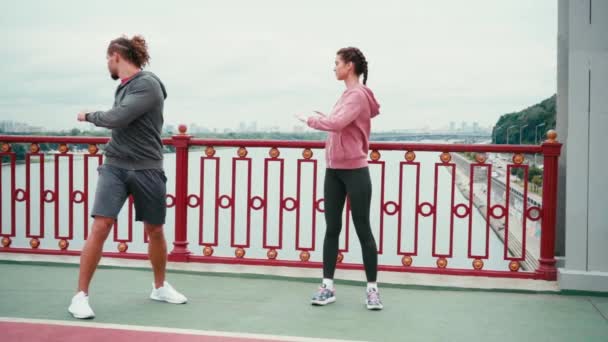 Paar Sportkleidung Streckt Sich Auf Brücke Mit Stadt Hintergrund Zeitlupe — Stockvideo