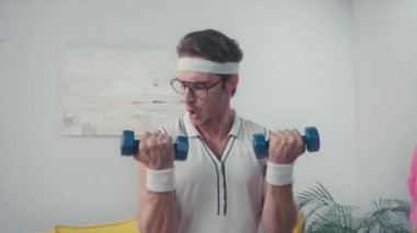 Gözlüklü sporcu evde dambıl kaldırıyor, retro spor konsepti.