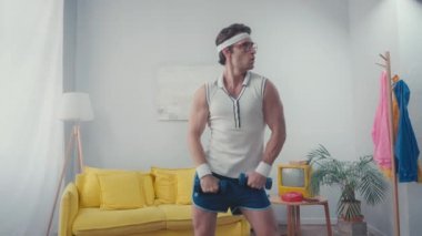 Sporcu oturma odasında kalçalarını sallarken dambılları kaldırıyor.